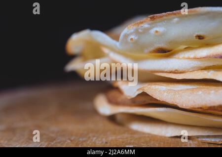 Primo piano di pancake appena sfornati impilati su un asse di legno Foto Stock