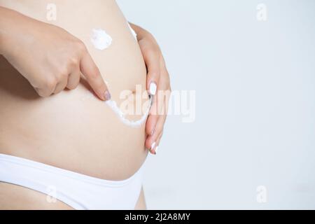donna carezzandogli il ventre mentre si alza su uno sfondo bianco Foto Stock