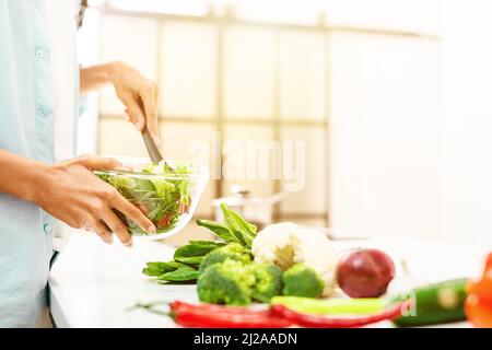 La giovane donna in cucina prepara un'insalata genuina con verdure fresche Foto Stock