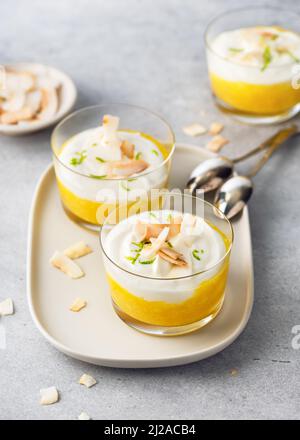 Dessert alla crema di frutta tropicale con strati bianchi e arancioni di purea di mango e formaggio cremoso. Cibo vegano. Foto Stock