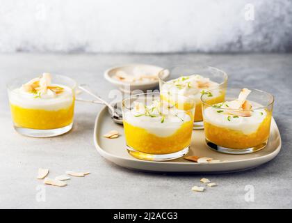 Dessert vegetariano alla crema di frutta con cagliata di latte di cocco e purea di mango in vasetti di vetro. Foto Stock