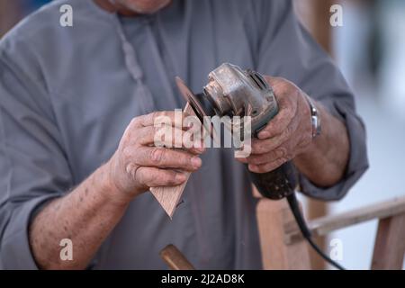 Mani del lavoratore Dettagli della macchina taglierina di legno con una sega circolare e asse di legno Foto Stock
