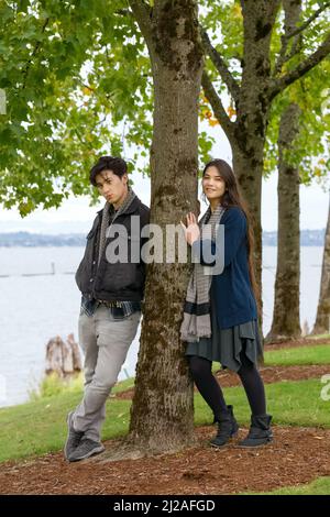 Giovane coppia biraciale in piedi insieme al lago nel parco Foto Stock