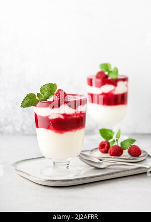 Dolce sano alla crema di frutta estiva con strati rossi e bianchi di salsa di lamponi e crema di latticello. Foto Stock
