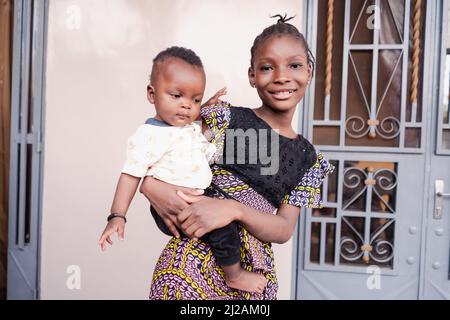 La sorella maggiore, orgogliosa e responsabile, si prende cura del suo fratellino, che lei porta nelle braccia come una questione naturalmente secondo la tradizione africana e f Foto Stock