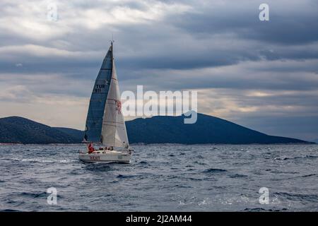 Bodrum, Mugla, Turchia - 02.25.2022: Imbarcazione a nave singola con vele aperte che navigano nel mar Egeo in regata. Vela vela in grigio vento tempo. Squadra Foto Stock