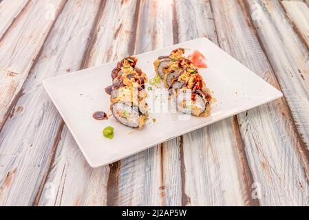 Sushi grasso di maki roll con alghe nori, formaggio cremoso, salsa di soia, cipolla croccante, avocado e erba cipollina fresca Foto Stock