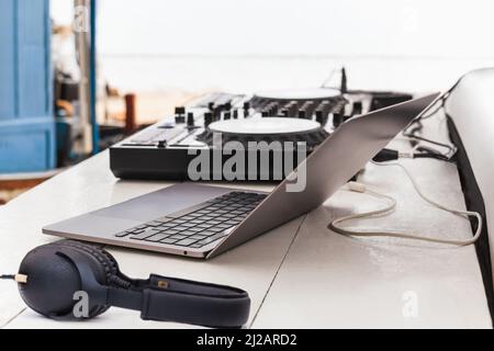 DJ sound control table mixing con cuffie e computer portatile su tavolo all'aperto. Foto Stock