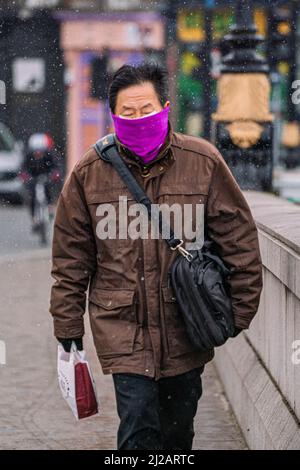 LONDRA, REGNO UNITO. 31 marzo 2022. Un pedone affronta le condizioni fredde del viticolo sul ponte Putney, a sud-ovest di Londra, durante le nevicate. L'ufficio MET ha emesso avviso meteo con ghiaccio, neve e freddo previsto per colpire parti Inghilterra credito: amer Ghazzal / Alamy Live News Foto Stock