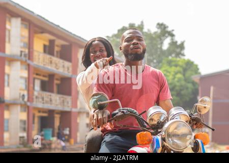 Primo piano di una donna africana che mostra la direzione del motociclista. Foto Stock