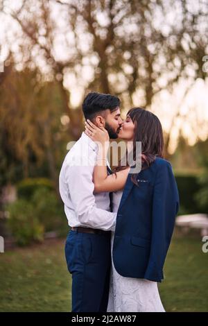 Potrei baciarti mille volte di più. Scatto corto di una giovane sposa affettuosa che bacia il suo sposo mentre indossa la sua giacca il giorno del loro matrimonio. Foto Stock