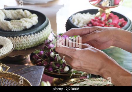 Donna a mano che fa belle ghirlande o ghirlande con Amaranth Flower, la ghirlande in stile tradizionale tailandese. Foto Stock