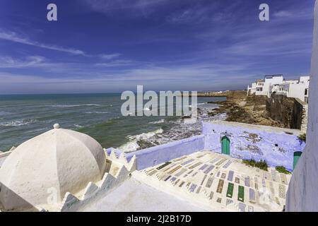 Ammirando l'antica fortezza fronte oceano di Asilah, Marocco. Pareti dipinte di bianco e blu di case che ricordano la città antica. Foto Stock