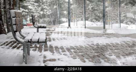 Bandiera panoramica di una panca parco coperta di neve nel parco Foto Stock