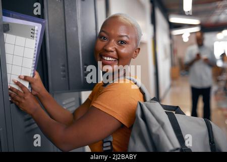 Primo piano di giovane donna nera che mette il notebook via in armadietto scuola Foto Stock