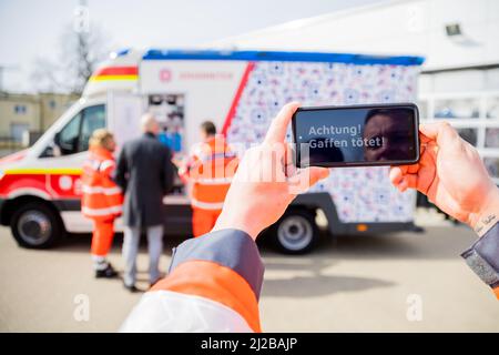 31 marzo 2022, Brandeburgo, Angermünde: David Sohn, paramedico di Johannitre-Unfall-Hilfe Angermünder, utilizza uno smartphone per dimostrare come funziona la prima ambulanza di Brandeburgo con un "design anti-gaffer". Johannitre-Unfall-Hilfe ha messo in funzione un'ambulanza con "design anti-Gaffer". In questo modo, Johannitre-Unfall-Hilfe vuole impedire le riprese del telefono cellulare da parte dei gaffer a gravi incidenti. Foto: Christoph Soeder/dpa Foto Stock