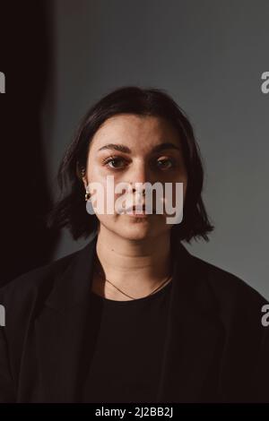Ritratto di donna seria su sfondo grigio Foto Stock