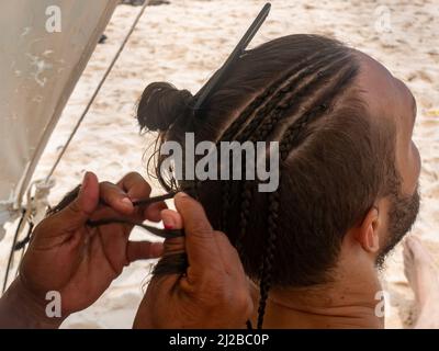 Marrone le mani della donna che brasano i capelli di un uomo bianco Foto Stock