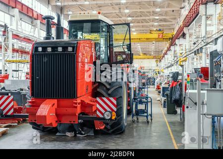 La vendemmiatrice o il trattore rosso di grandi dimensioni sono in fase di assemblaggio in fabbrica per la produzione di macchinari agricoli. Foto Stock
