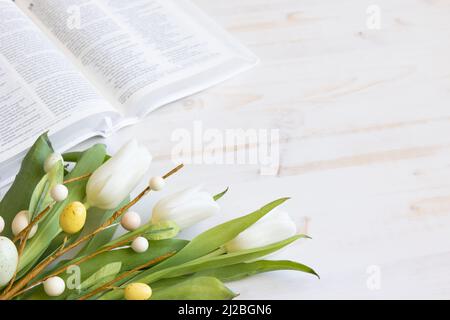 bibbia bianca con tulipani bianchi e decorazioni delle uova di pasqua su legno bianco con spazio copia Foto Stock