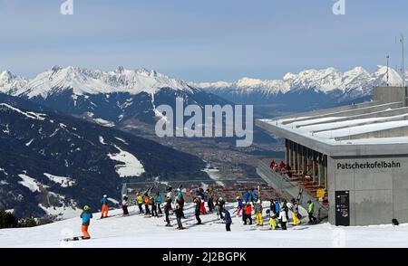 Gli sciatori si radunano fuori dal ristorante Das Kofel presso la stazione di montagna del Patscherkofelbahn, mentre la gondola sorge sopra la valle dell'Inn e Innsbruck. Foto Stock