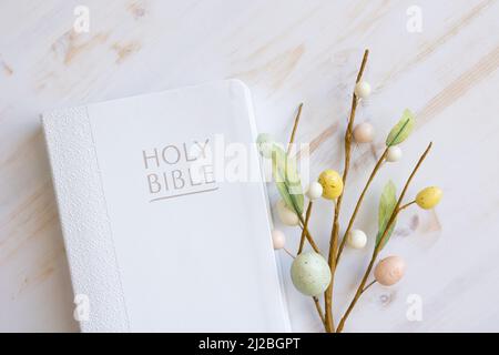 bibbia bianca con tulipani bianchi e decorazioni delle uova di pasqua su legno bianco con spazio copia Foto Stock