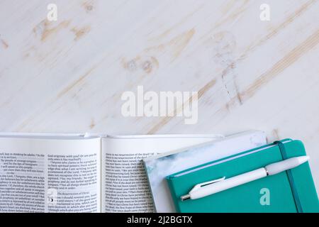 Christian bible, teal journal, penna bianca su una scrivania di legno bianco con spazio copia girato dall'alto Foto Stock