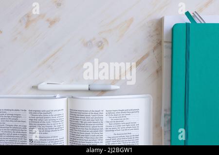 Christian bible, teal journal, penna bianca su una scrivania di legno bianco con spazio copia girato dall'alto Foto Stock