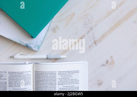 Christian bible, teal journal, penna bianca su una scrivania di legno bianco con spazio copia girato dall'alto Foto Stock