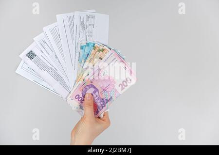 Le banconote di hryvnia e i pagamenti per i servizi pubblici sono nelle mani di una persona. 21 marzo 2022, Zaporozhye, Ucraina. Foto Stock