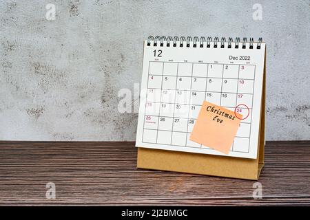 Calendario del 2022 dicembre su scrivania in legno con cerchio di data e testo su nota adesiva. Vigilia di Natale il 24th dicembre 2022 Foto Stock