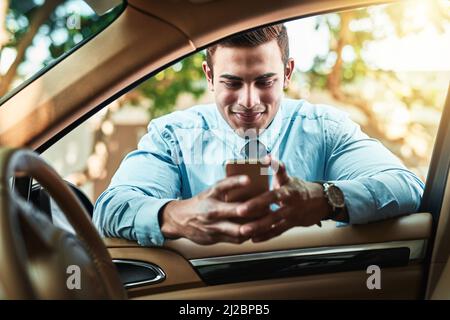 Rimanere vicino alla sua rete anche quando è in movimento. Colpo di un giovane uomo d'affari usando un cellulare mentre si appoggia contro la sua auto. Foto Stock