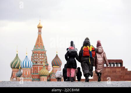Persone che camminano sulla Piazza Rossa di Mosca sullo sfondo della Cattedrale di San Basilio e del Mausoleo di Lenin. Donna con due ragazze in primo piano Foto Stock