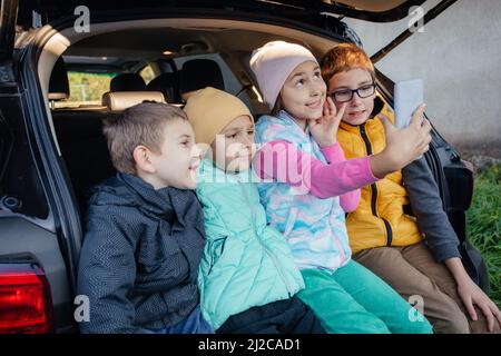 Gruppo di bambini che prendono selfie con smartphone seduto in auto Foto Stock