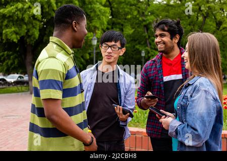 Un gruppo di studenti diversi comunica facilmente dopo le lezioni universitarie. Stabilire forti legami tra giovani di razze e nazionalità diverse Foto Stock