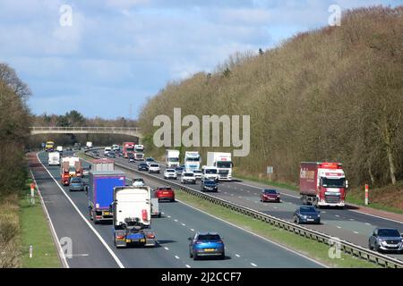 Traffico che scorre su entrambe le carreggiate a tre corsie dell'autostrada M6 in Lancashire mentre passa il villaggio di Scorton in un pomeriggio soleggiato nel marzo 2022. Foto Stock