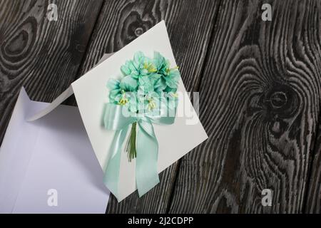 Biglietto d'auguri fatto in casa in toni verdi. Busta per una cartolina. Su tavole di pino. Foto Stock