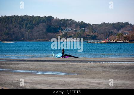 Persona che cammina su una spiaggia che si prepara ad alare il foglio Foto Stock