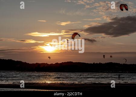 Gothenburg, Svezia - Ottobre 10 2021: Kiteboarders kitesurf al tramonto su una spiaggia Foto Stock