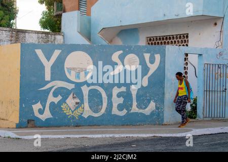 Donna che indossa un paio di infradito cammina accanto a un Yo Soy Fidel, io sono folle (Castro) murale tributo a Trinidad, Cuba. Foto Stock