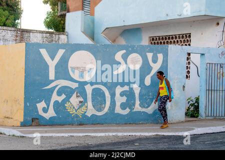 Donna che indossa un paio di infradito cammina accanto a un Yo Soy Fidel, io sono folle (Castro) murale tributo a Trinidad, Cuba. Foto Stock