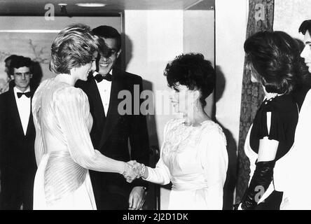 La principessa Diana scrolla le mani con l'attrice Joan Collins ad un Soiree di moda di Bruce Oldfield London tenuto a Grosvenor House a Londra in aiuto della carità Barnardos, di cui è appena diventata presidente e dove il progettista è stato portato up.The Princess sta portando un pleated, aperto indietro, Odeon drappeggiato di raggi solari in argento e oro zoppo, progettato da Bruce Oldfield. 26th marzo 1985. Foto Stock