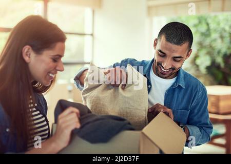 Theyre eccitato per cominciare depositarsi nel loro nuovo nido. Scatto corto di una giovane coppia che disimballo scatole mentre si sposta nella loro nuova sede. Foto Stock