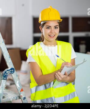 Giovane donna costruttore con documenti in cantiere Foto Stock