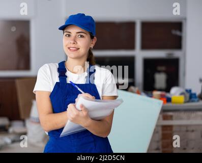 Giovane donna costruttore con documenti in cantiere Foto Stock