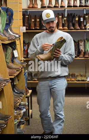 Un uomo della generazione Z che naviga attraverso un negozio di abbigliamento occidentale, il Wrangler, nel centro di Cheyenne Wyoming nell'agosto 2021 Foto Stock