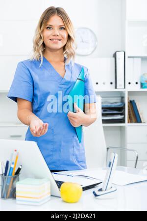 Ragazza medico sorge nei pressi di un tavolo in ufficio Foto Stock