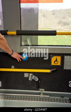 Una mano uomo adulto che preme il pulsante blu della porta persone disabili in autobus di trasporto pubblico a Parigi, Francia Foto Stock