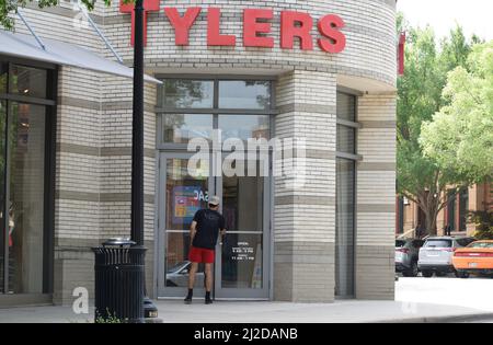 Gen Z uomo in pantaloncini rossi e maglietta nera a piedi in un negozio a Southlake Town Square; Southlake, Texas Foto Stock