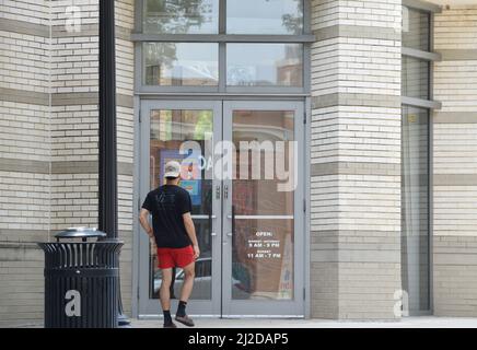 Gen Z uomo in pantaloncini rossi e maglietta nera a piedi in un negozio a Southlake Town Square; Southlake, Texas Foto Stock